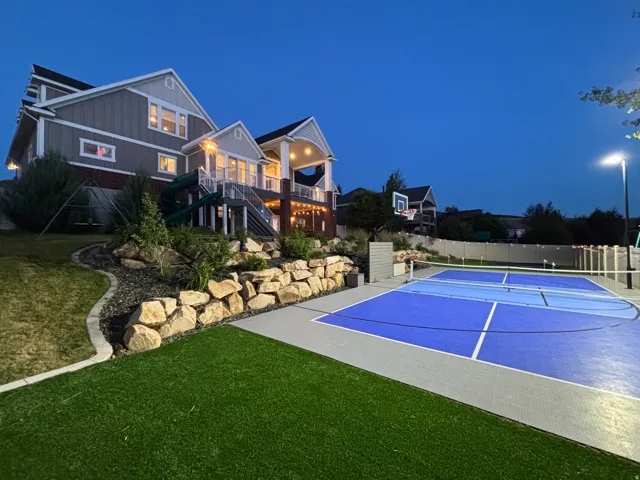 Multi-sport court featuring blue and grey surfacing, equipped with a basketball hoop and net