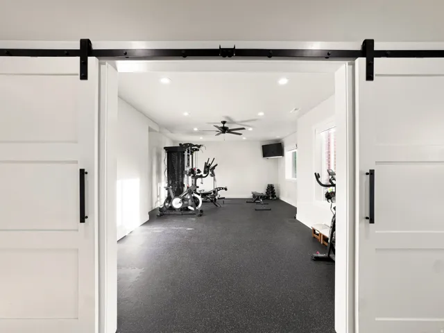 Interior space featuring barn doors with matte black hardware, recessed lighting, and a ceiling fan