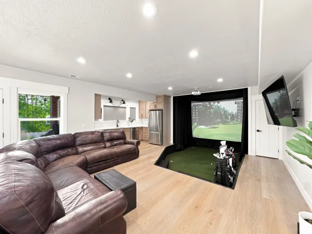 Recessed golf simulator, wood-finish flooring, kitchen cabinetry, stainless steel appliances, and built-in ceiling lighting