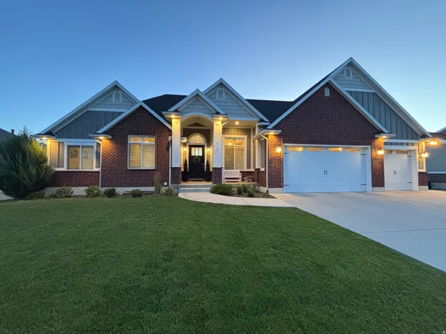 Brick and siding exterior featuring gabled rooflines, a covered front entry with columns, a manicured lawn, and an attached two-car garage with a single-car garage