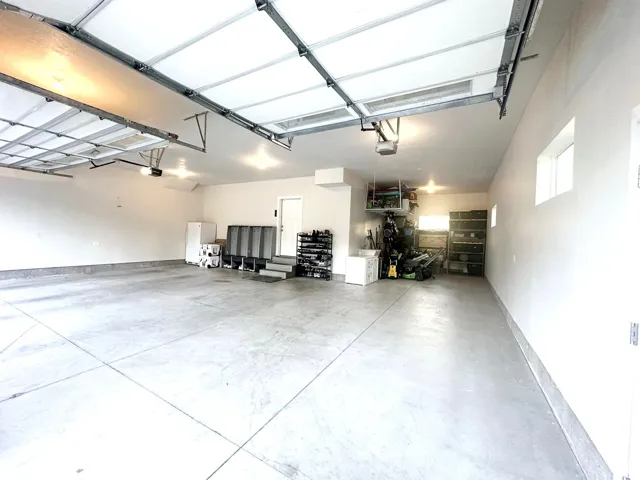 Spacious garage featuring a concrete floor, overhead garage doors, and built-in shelving