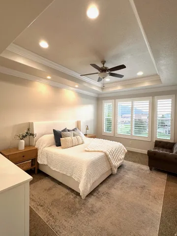Spacious room featuring a tiered tray ceiling with recessed lighting and crown molding
