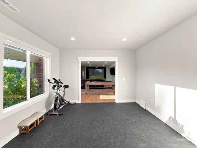 Recessed lighting, large window with white trim, dark textured flooring, white baseboards, and a framed doorway