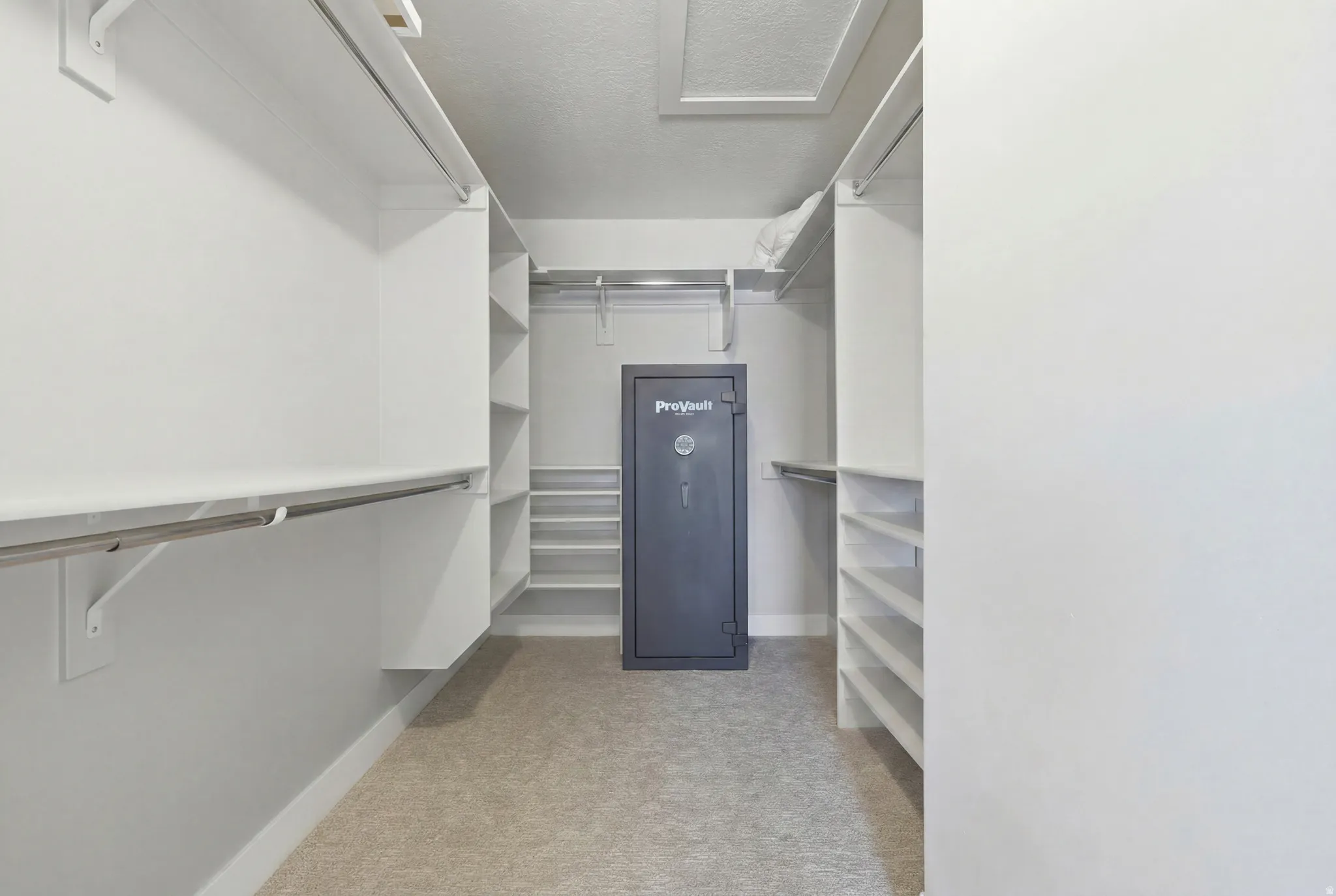Spacious walk-in closet featuring built-in shelving, hanging rods, and light-colored carpeting