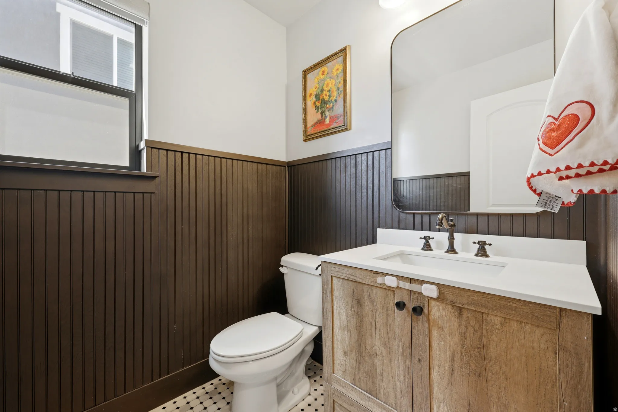Contemporary bathroom featuring beadboard wainscoting, a rustic wood-finish vanity with a white countertop, and a black-framed window
