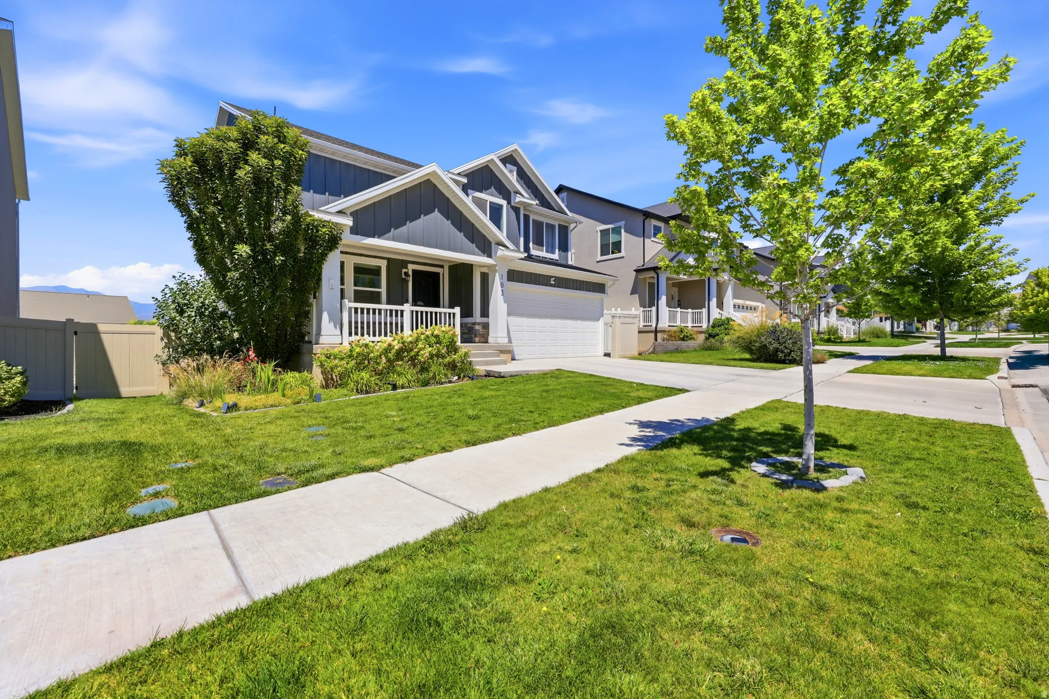 Contemporary home exterior featuring blue siding, white trim, and a covered porch with white railings