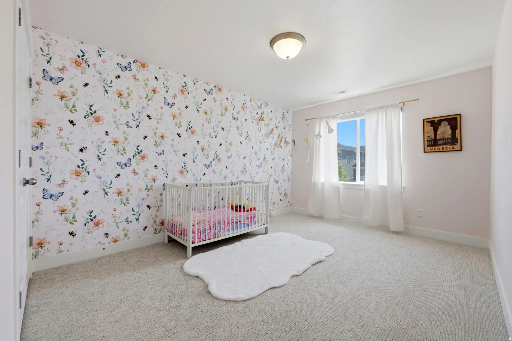 Interior room featuring a floral accent wall, light-toned carpeting, white trim, and a window with white drapes