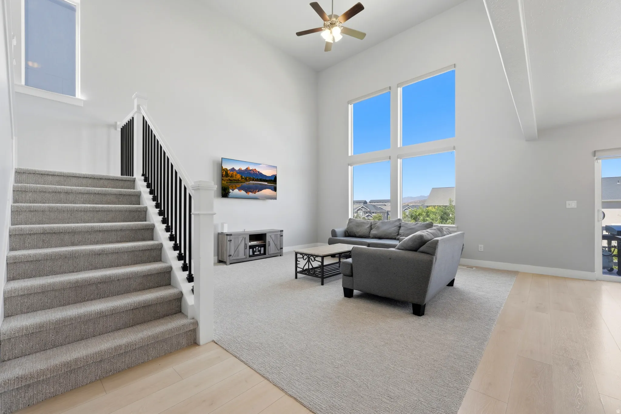 Two-story living area featuring a vaulted ceiling with exposed beams and a ceiling fan
