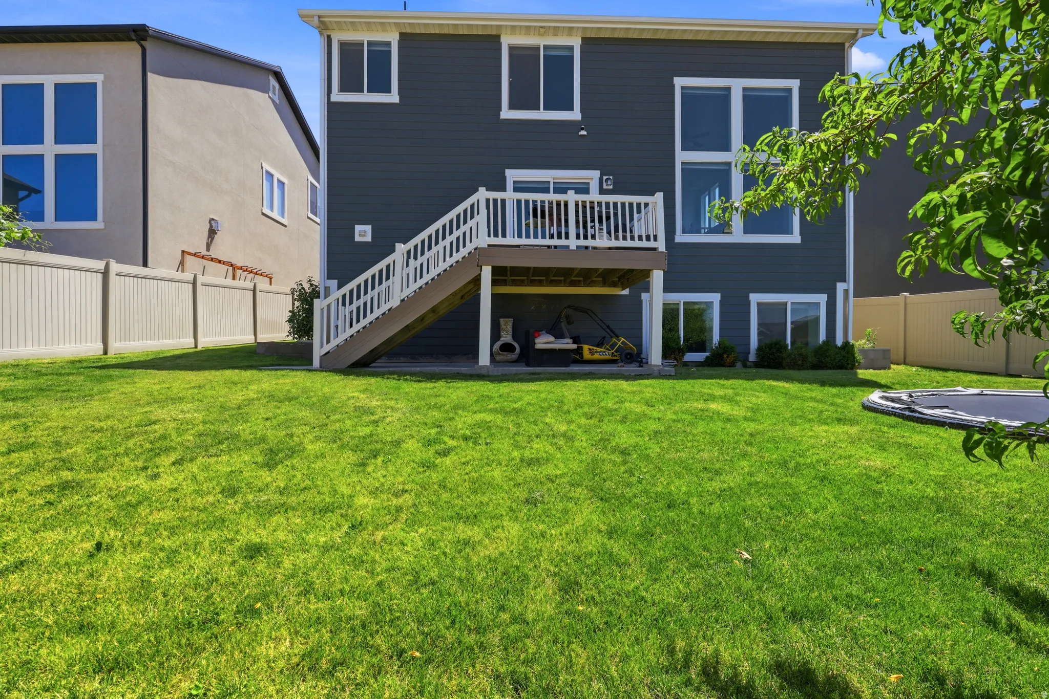 Expansive green lawn with a multi-level deck and patio