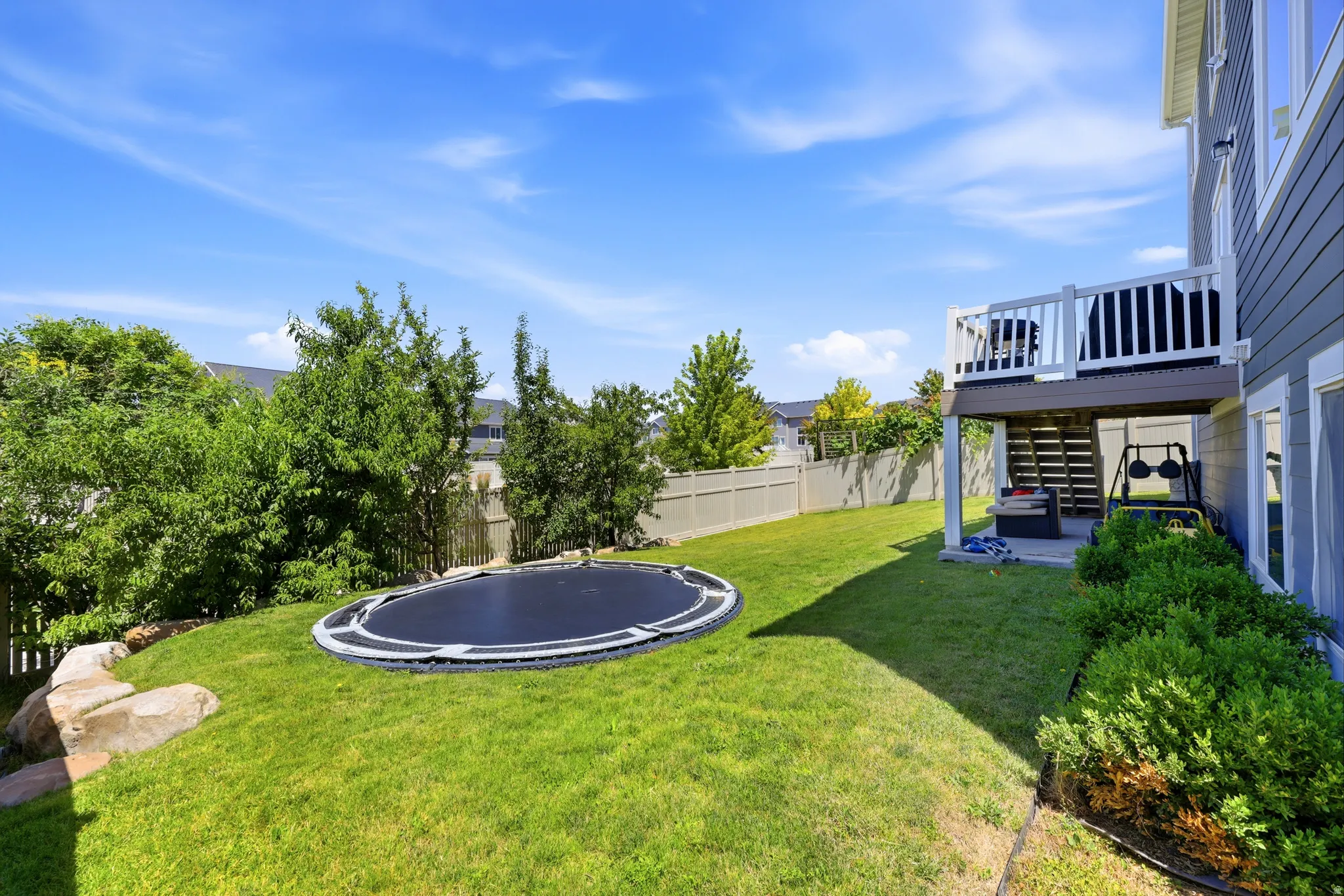 Expansive green lawn with mature landscaping and privacy fencing