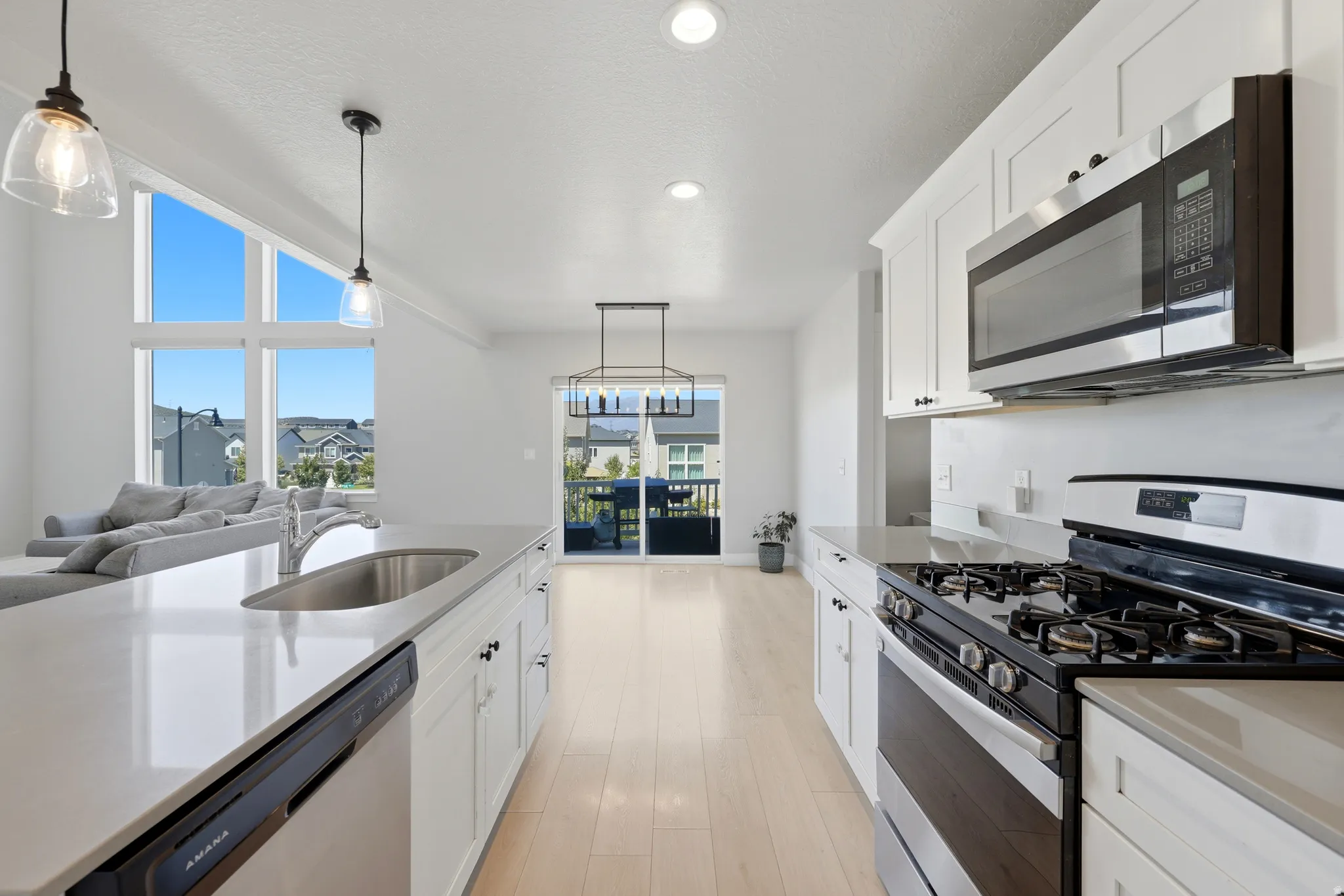 Open-concept kitchen featuring white cabinetry, light-toned wood-finish flooring, and white countertops