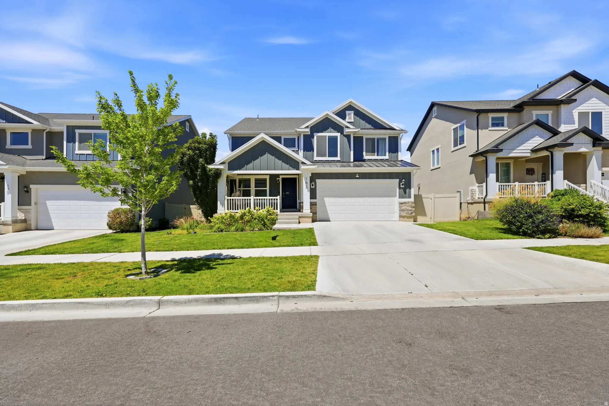 Two-story residence featuring a blue and grey facade with white trim, a covered front porch, and an attached two-car garage