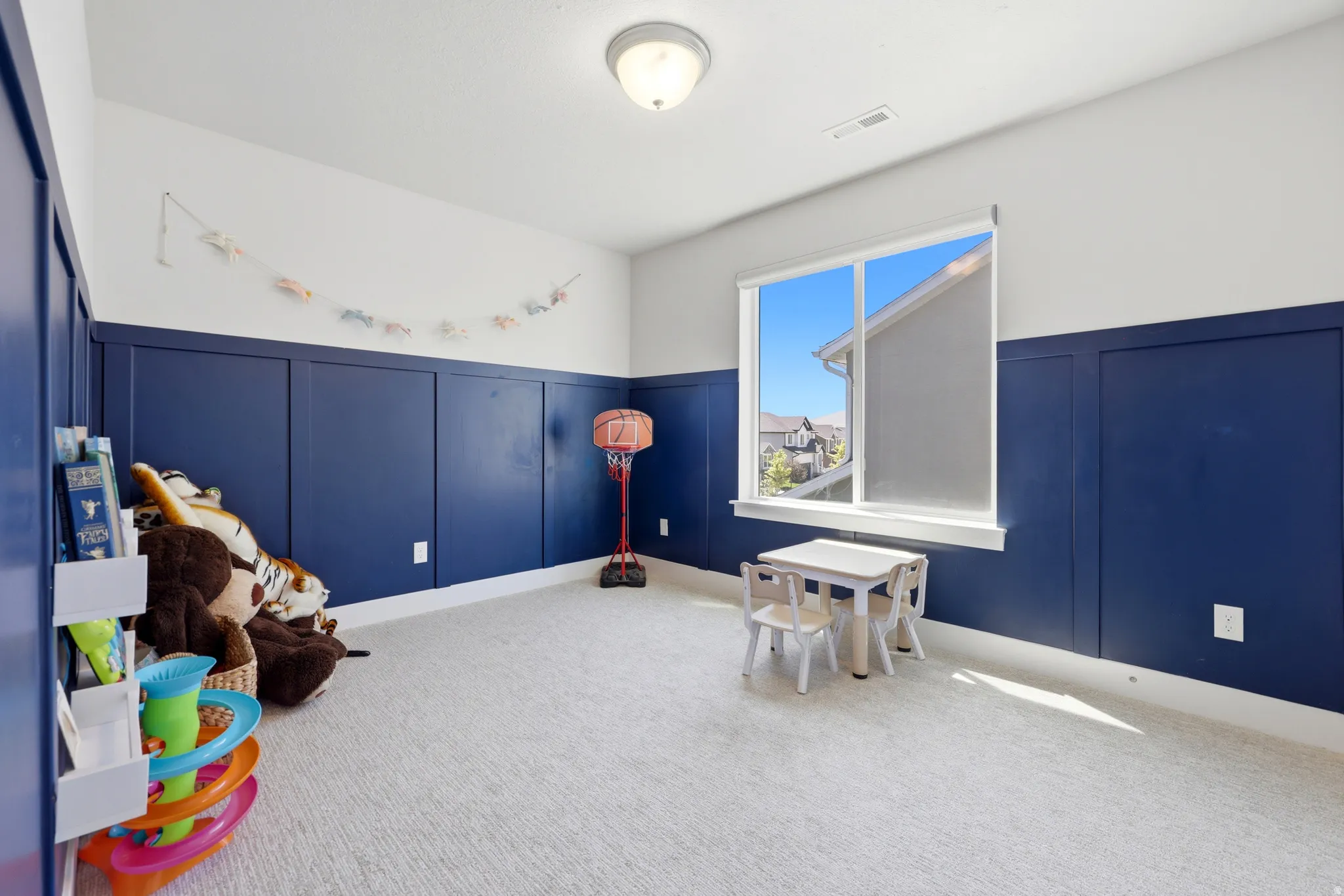 Room featuring board and batten wall detailing, light-toned carpeting, a large picture window, and a flush mount ceiling light fixture