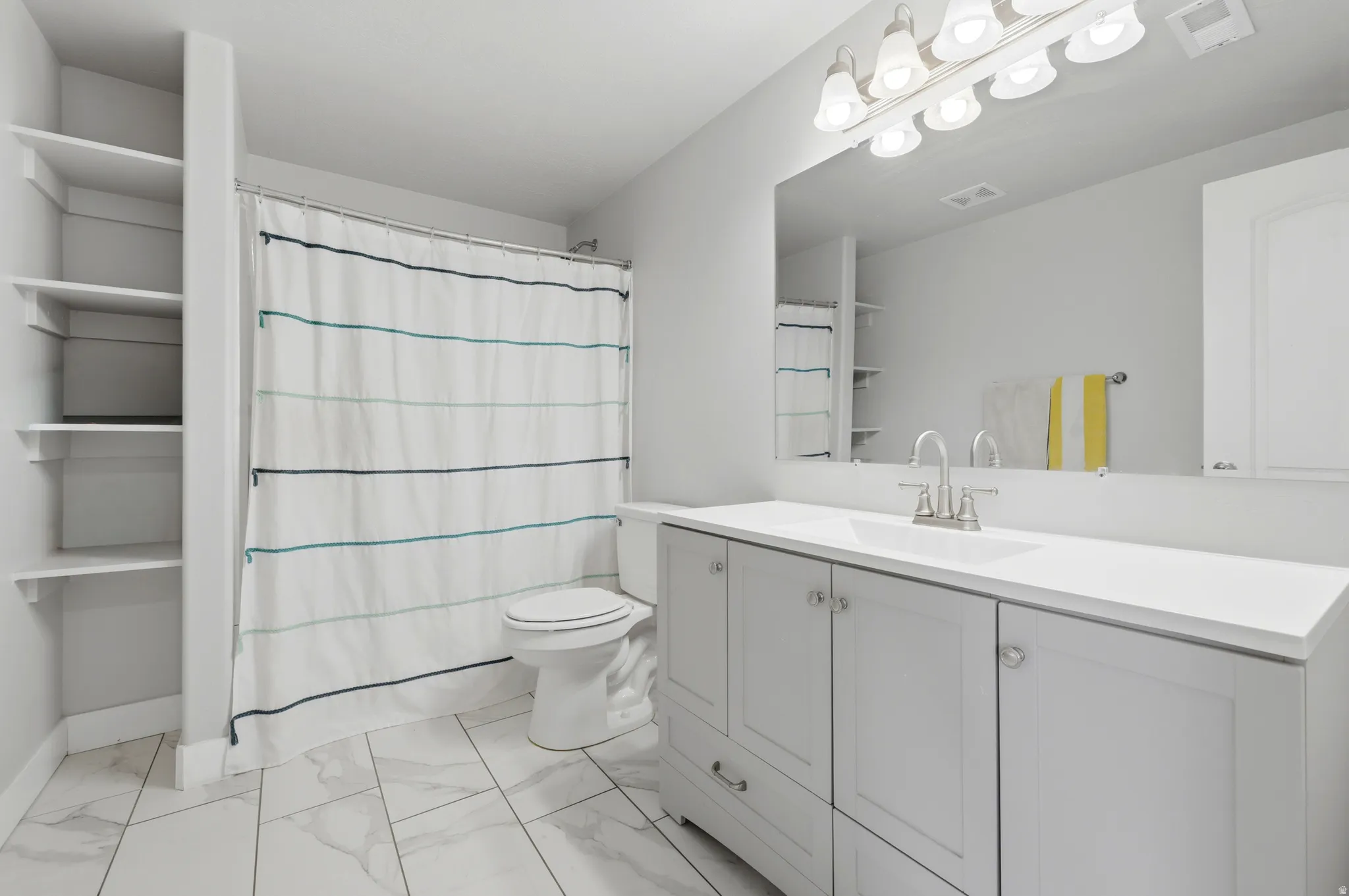 Bathroom featuring a single vanity with extensive countertop, built-in shelving, and light wood-finish flooring
