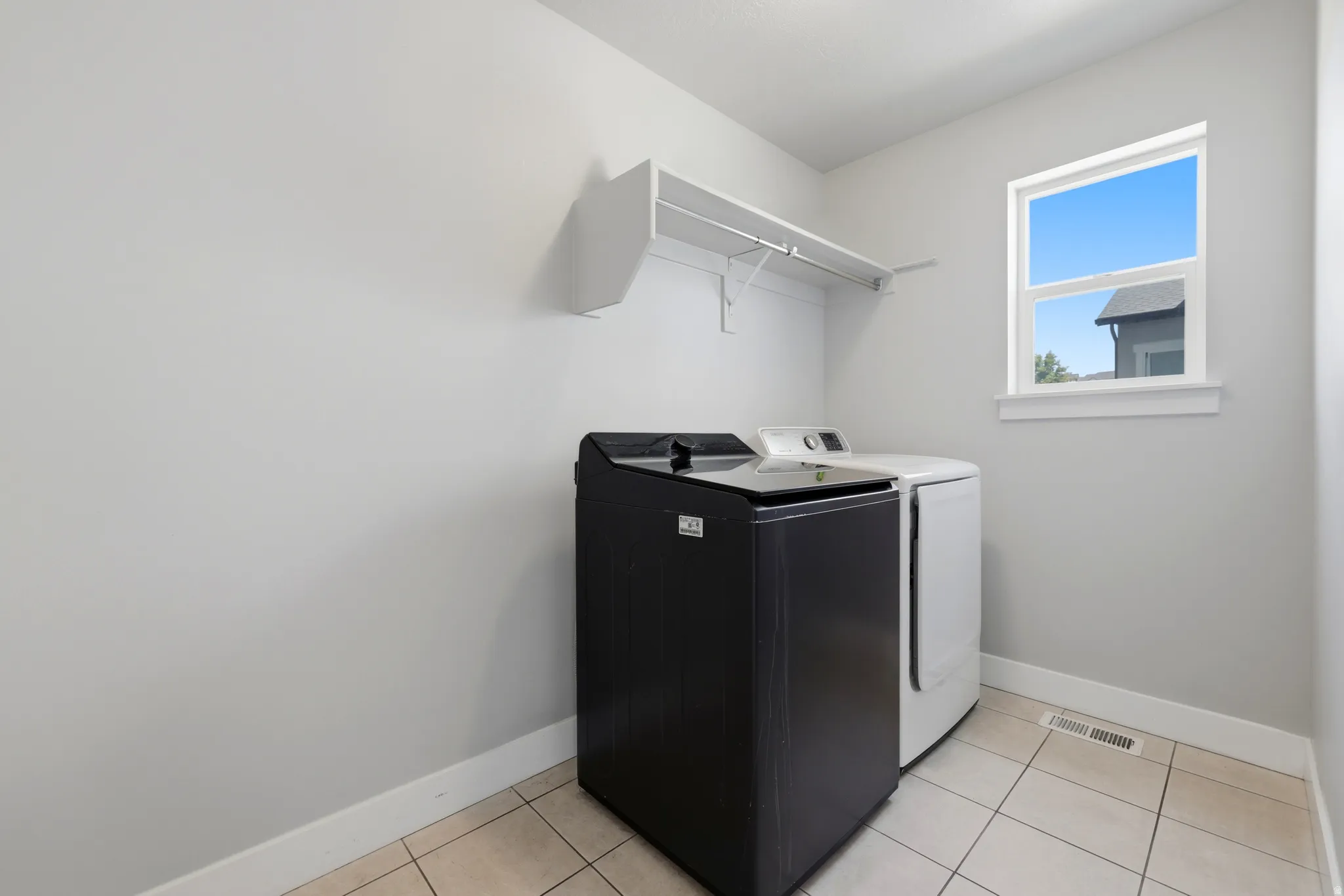 Utility room featuring a window with white trim, tile flooring, and wall-mounted shelving
