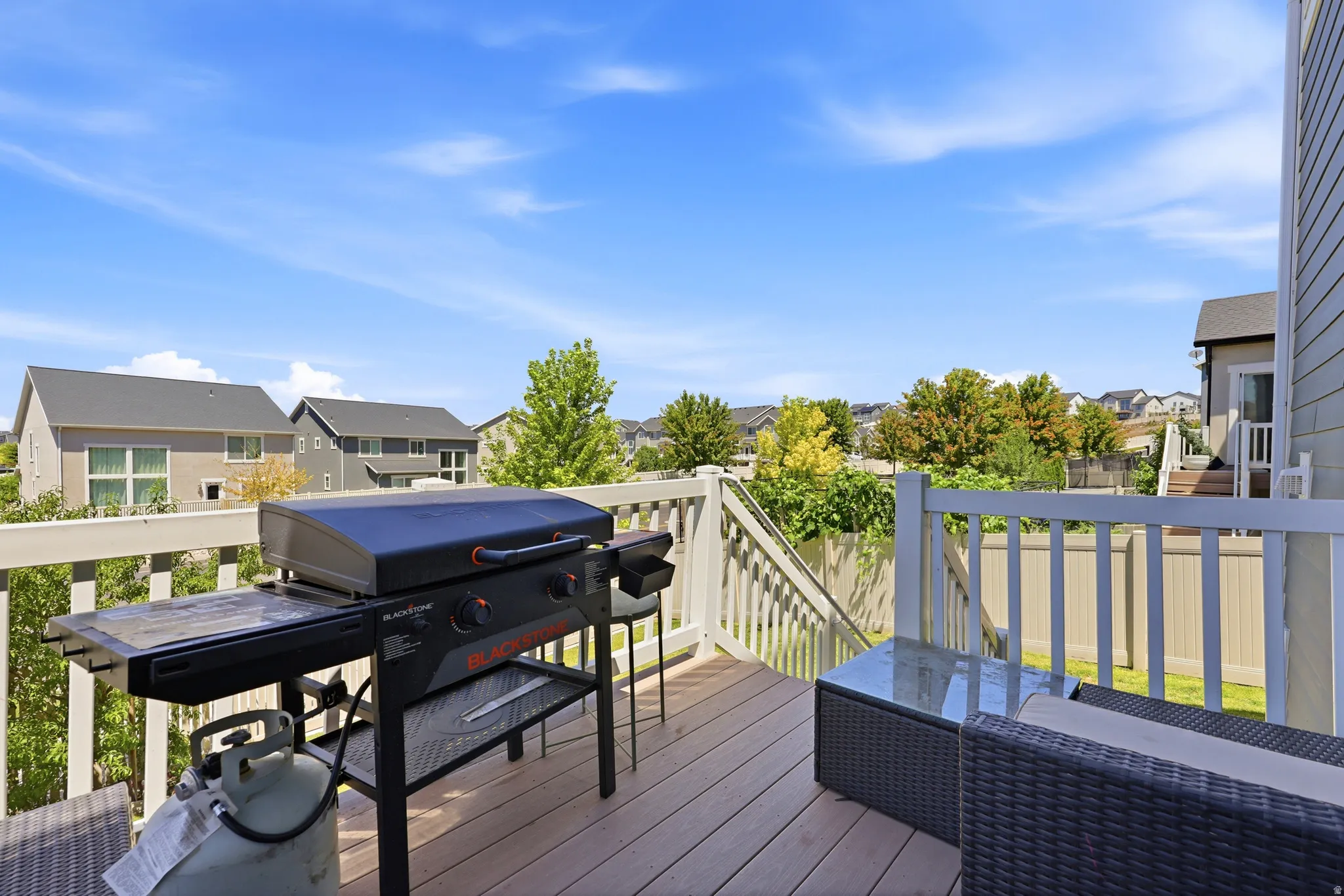 Spacious outdoor deck featuring wood-finish flooring, white railing, and exterior stairs