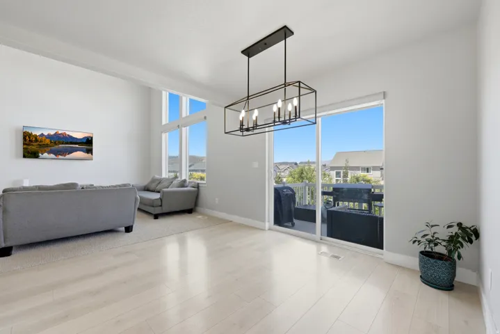 Open-concept living space featuring high ceilings, wood-finish flooring, a modern linear chandelier, and expansive windows