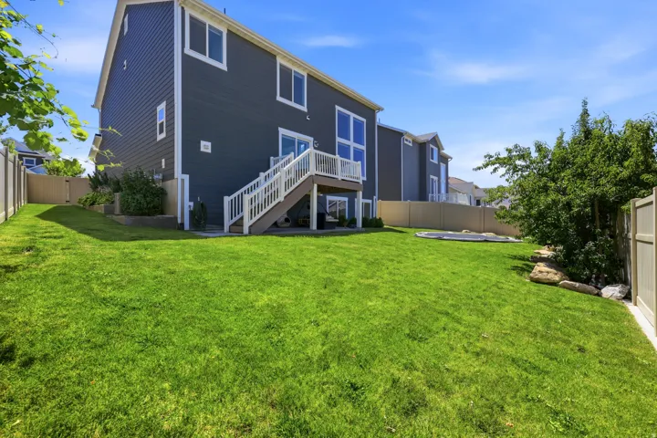 Spacious backyard featuring a manicured lawn, full privacy fencing, and a multi-level deck with white railings