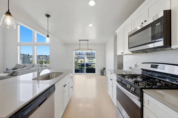 Open-concept kitchen featuring white cabinetry, light-toned wood-finish flooring, and white countertops