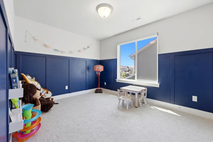 Room featuring board and batten wall detailing, light-toned carpeting, a large picture window, and a flush mount ceiling light fixture