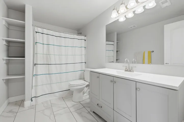 Bathroom featuring a single vanity with extensive countertop, built-in shelving, and light wood-finish flooring