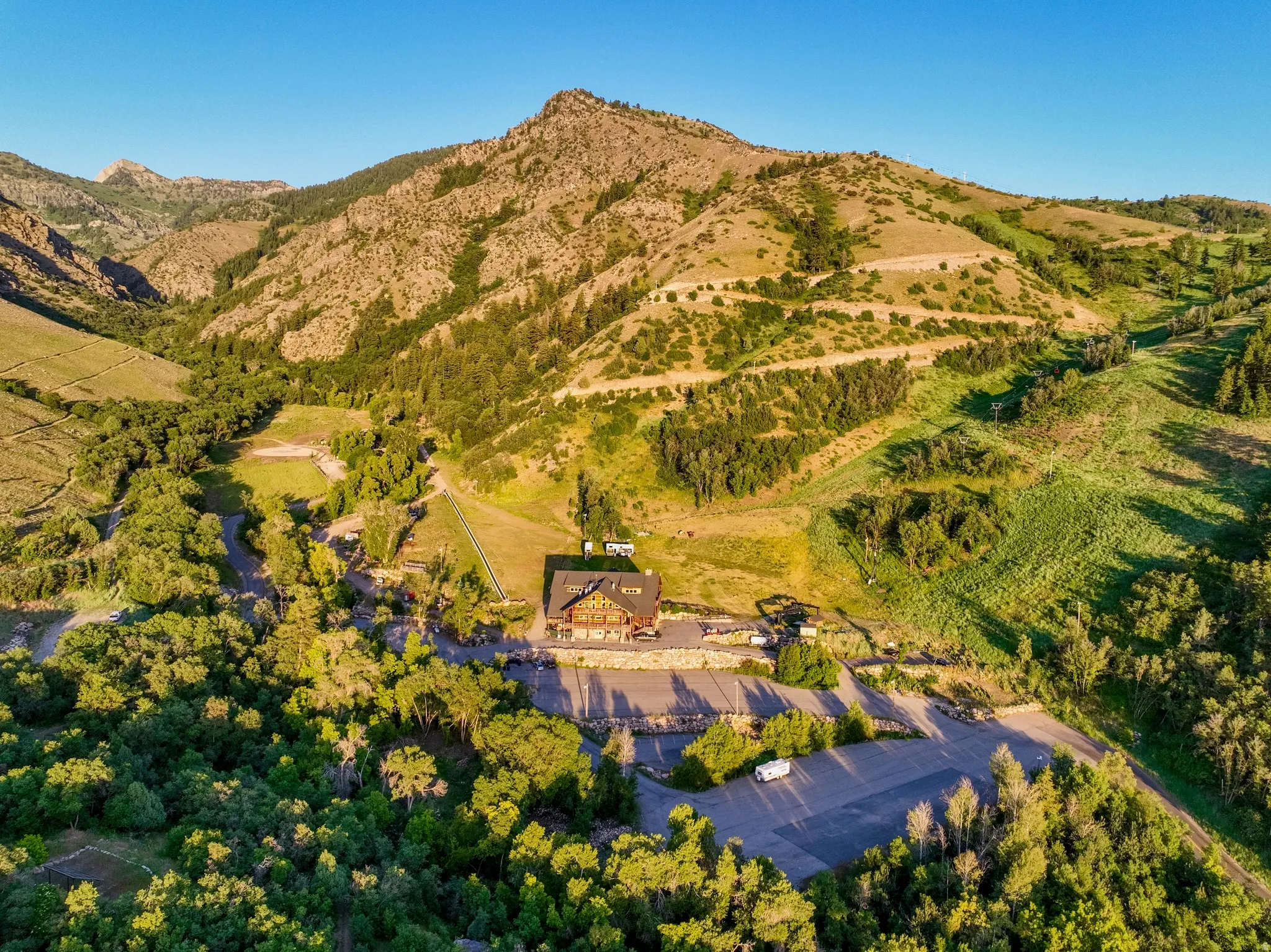 Expansive mountain property featuring a central lodge with a large paved parking area, surrounded by diverse natural terrain