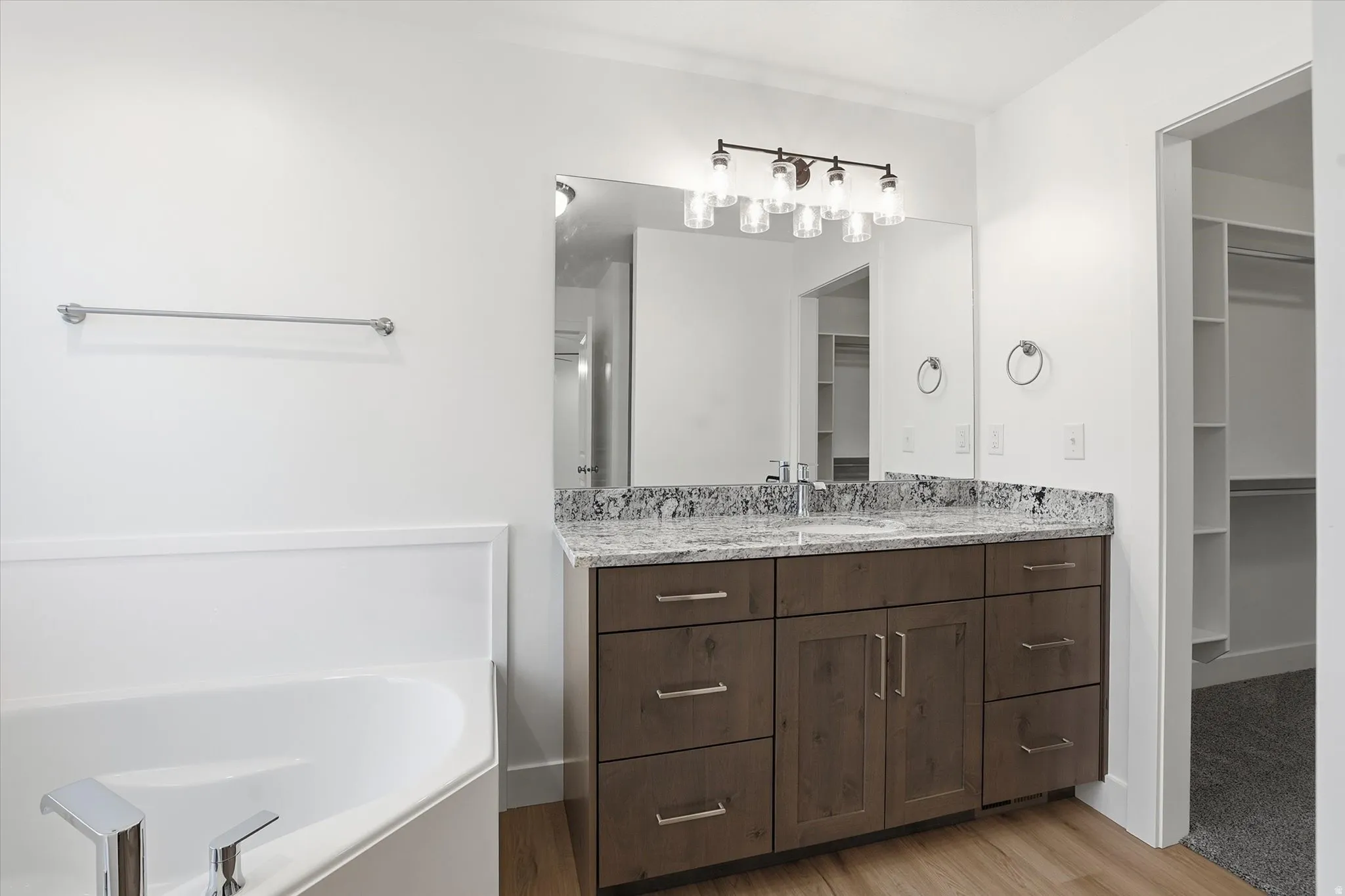Bathroom vanity featuring a granite countertop, undermount sink, and dark wood cabinetry with brushed nickel hardware