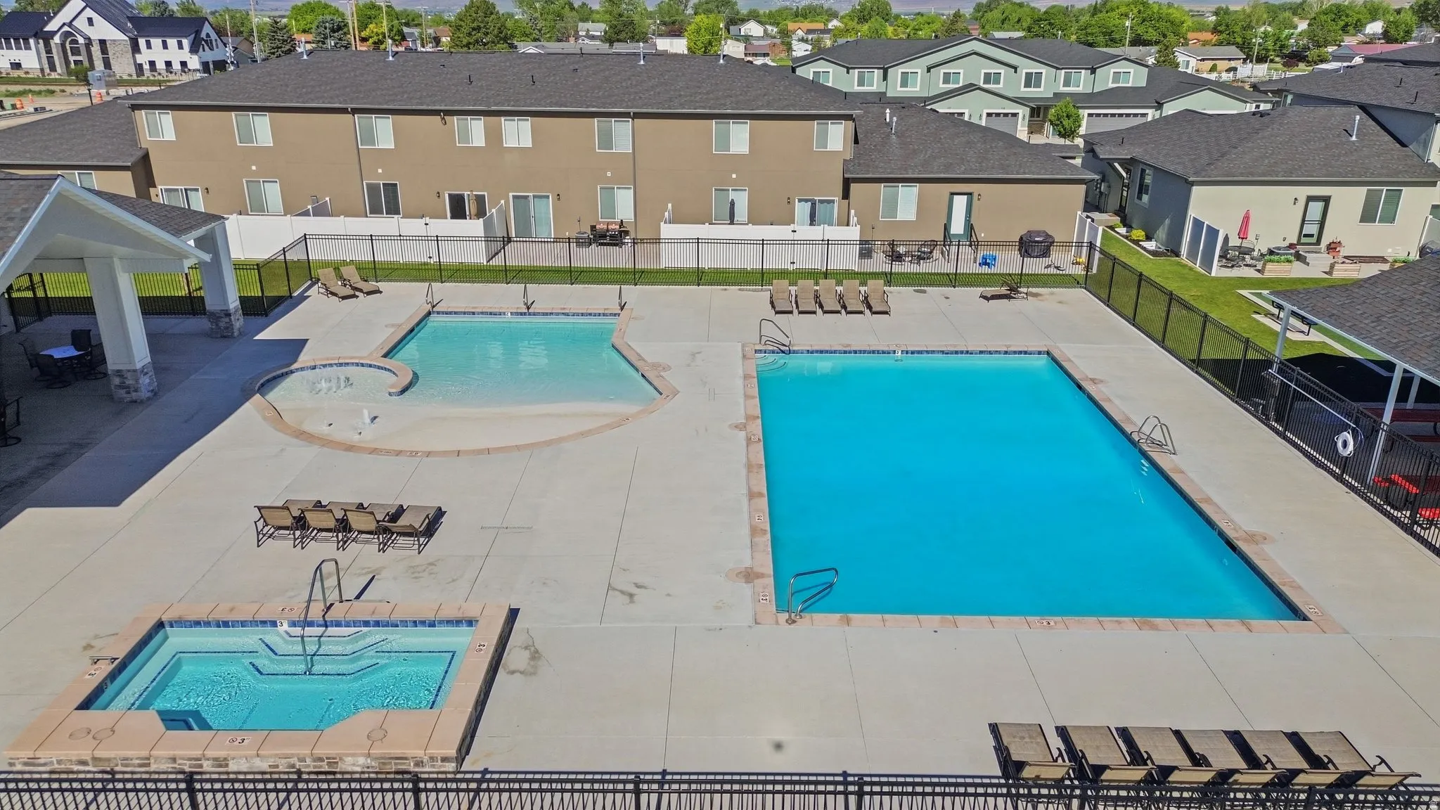 Community amenities featuring a large rectangular pool, a second pool with a beach entry, and a separate jetted spa