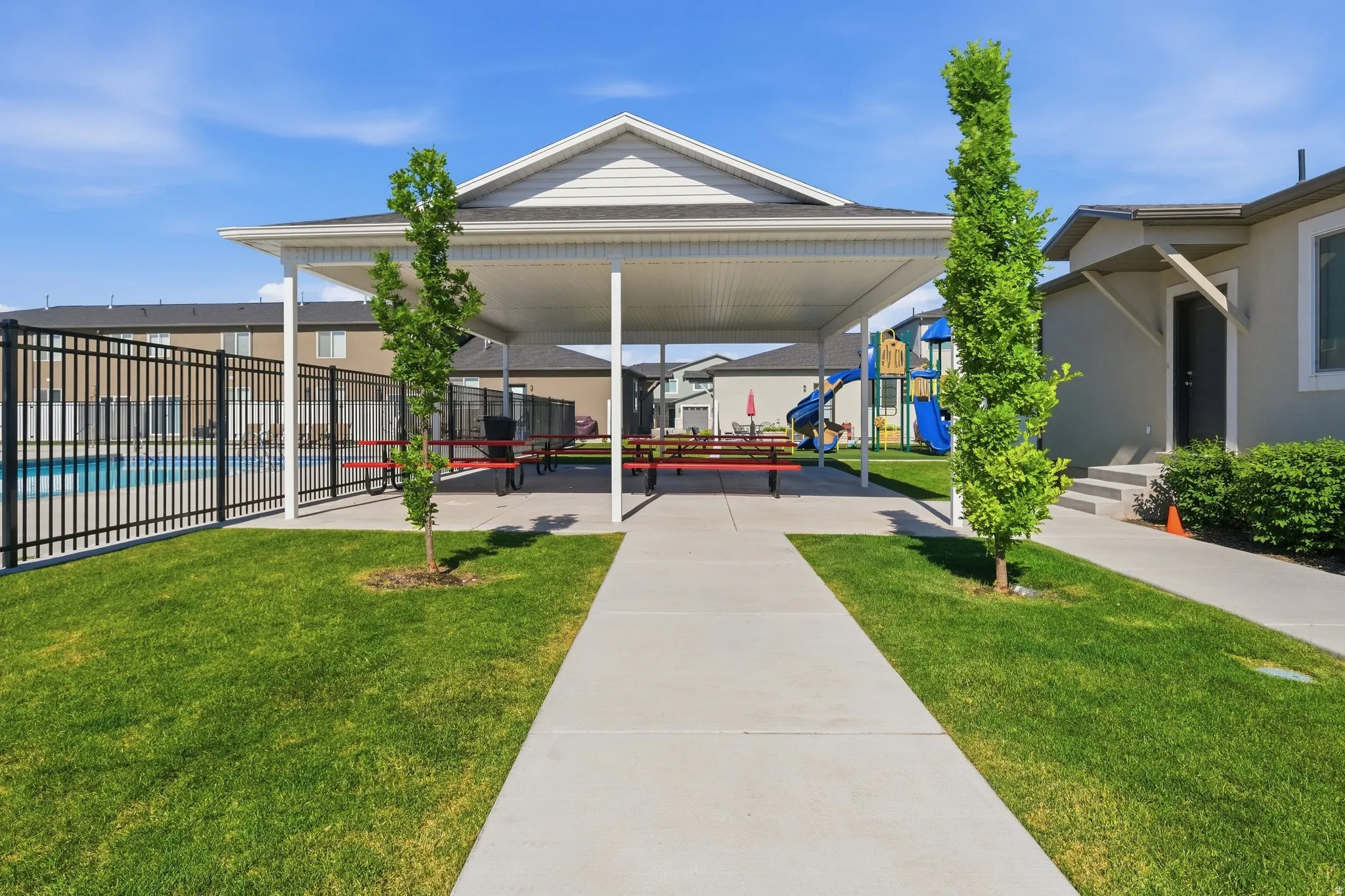 Covered patio area with concrete pathway, surrounded by manicured lawn