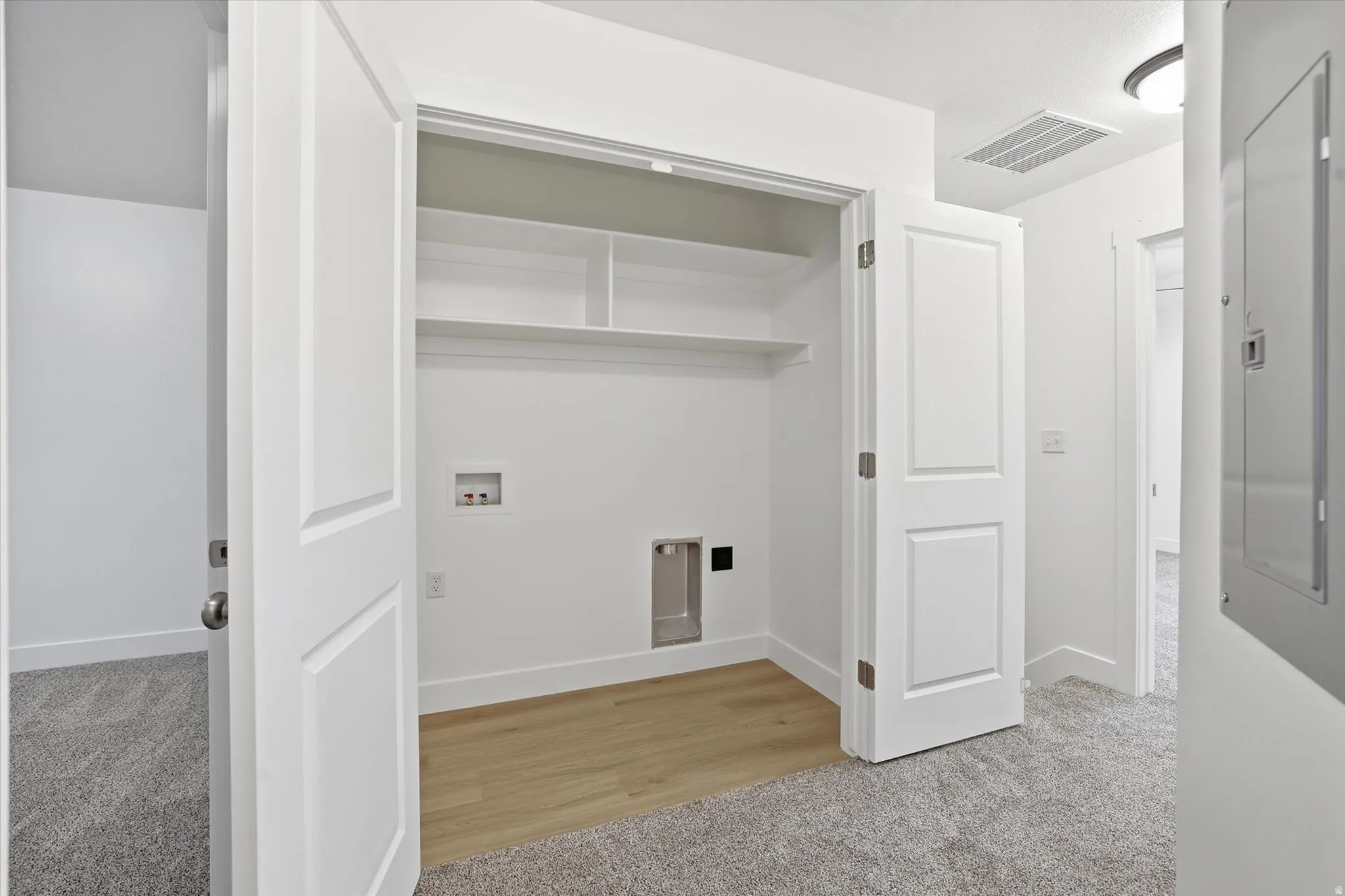 Dedicated laundry area featuring wood-finish flooring, white shelving, and utility hookups