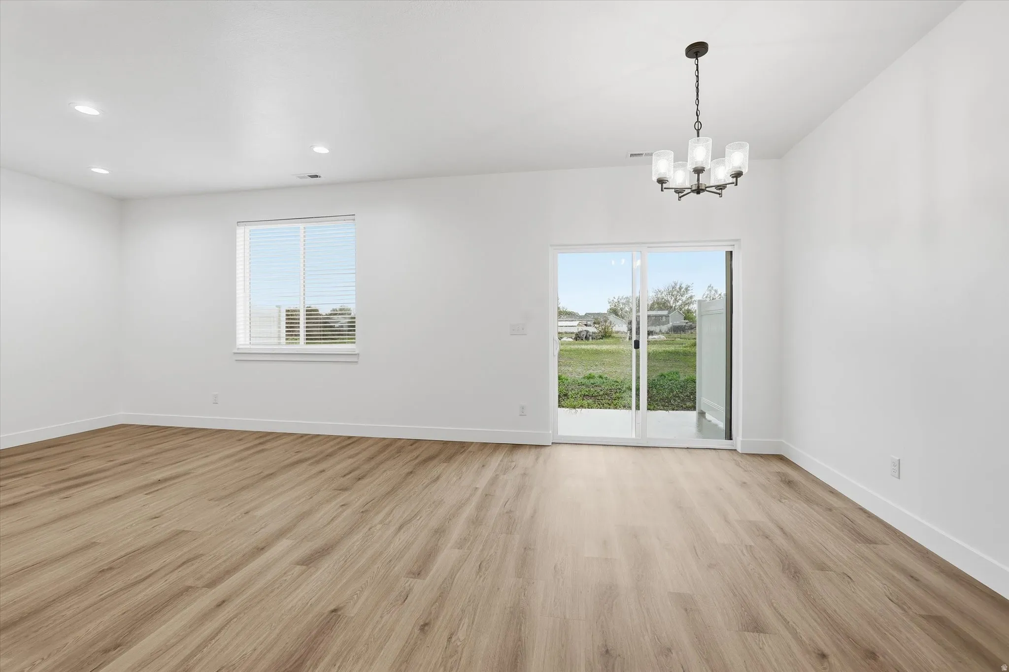 Open-concept interior featuring wood-finish flooring, recessed lighting, and a modern chandelier