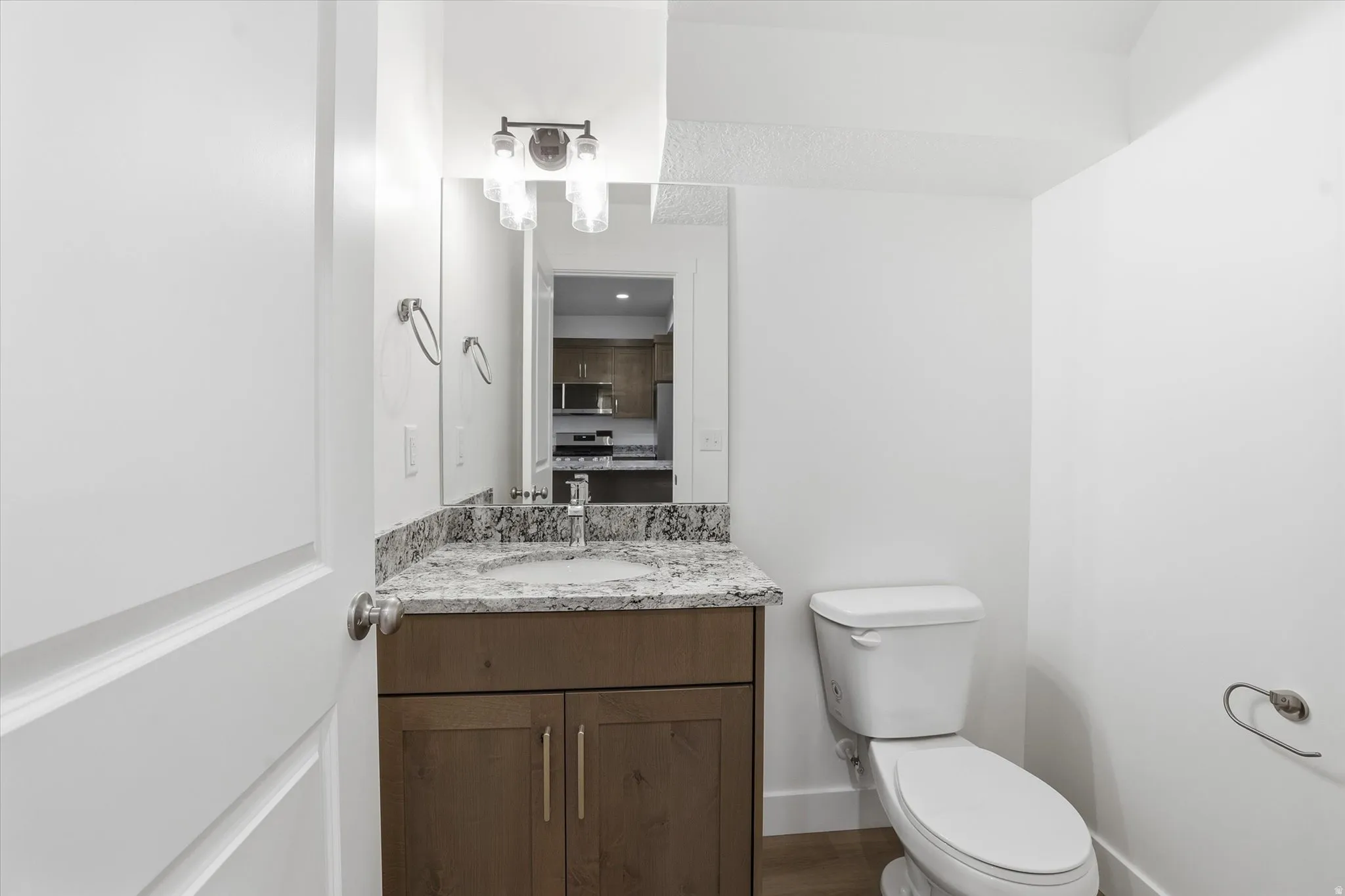 Contemporary bathroom featuring a dark wood-finish vanity with a light speckled countertop and undermount sink