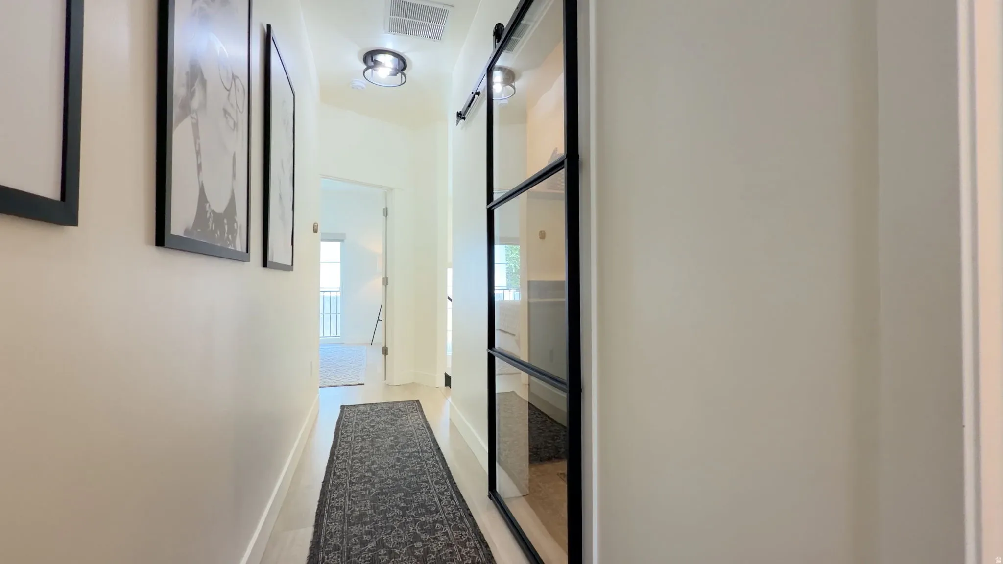 Hallway featuring wood-finish flooring, recessed lighting, and a modern barn door with glass panels