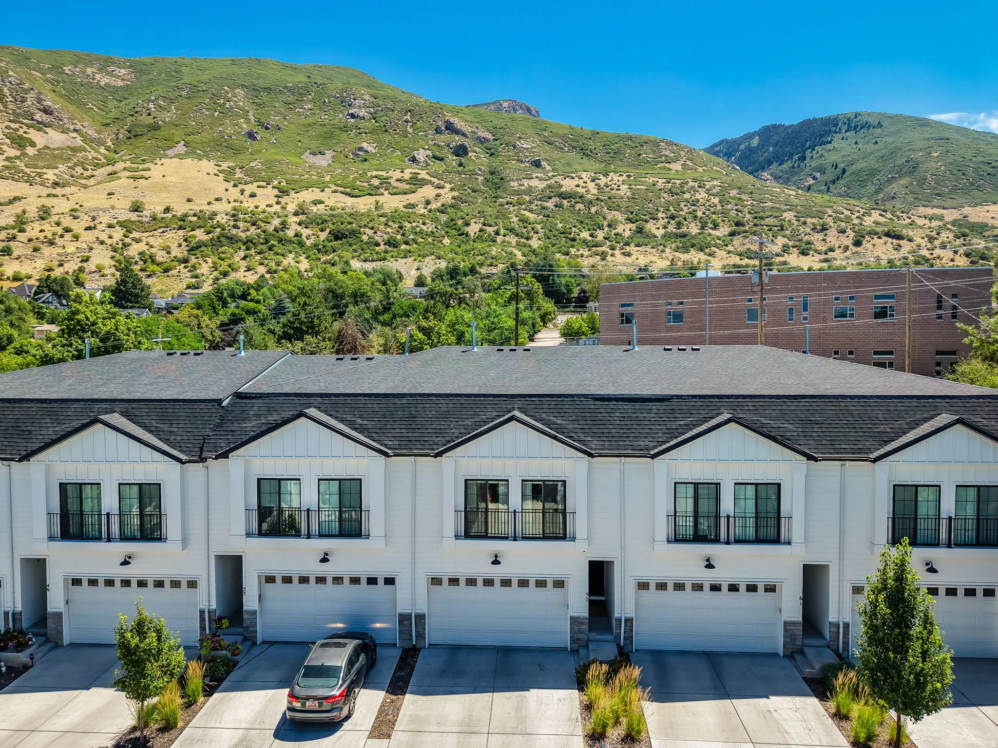 Contemporary townhome facade featuring white siding, black-framed windows, and mountain views