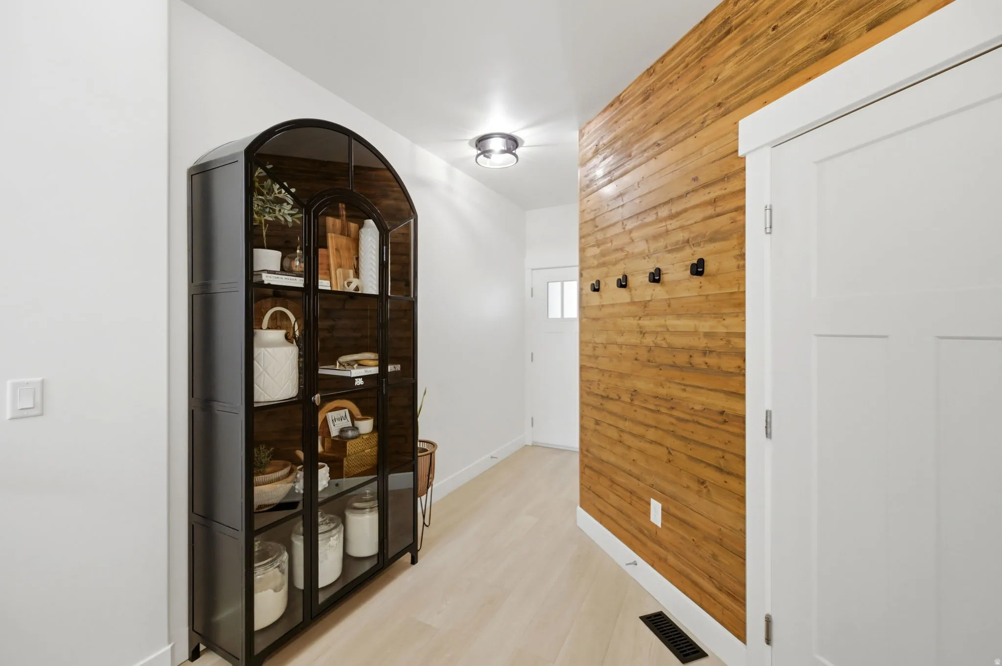 Entryway featuring a wood-panel accent wall with black wall hooks