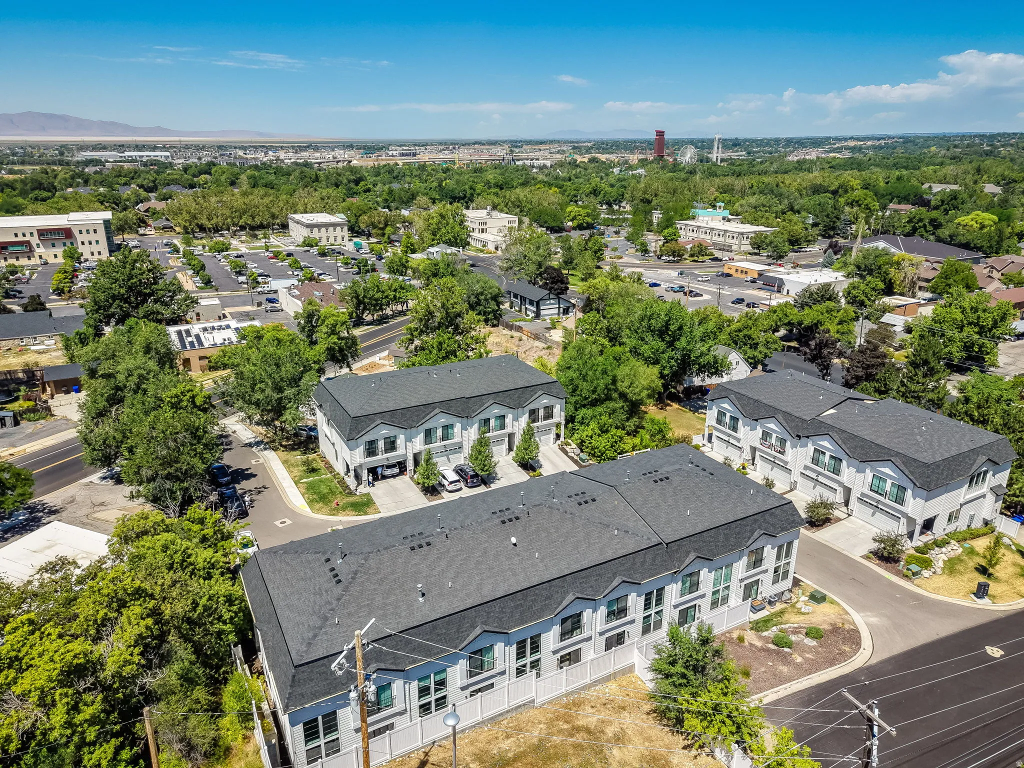 Modern townhome development featuring light-colored siding, dark shingle roofs, and multiple windows