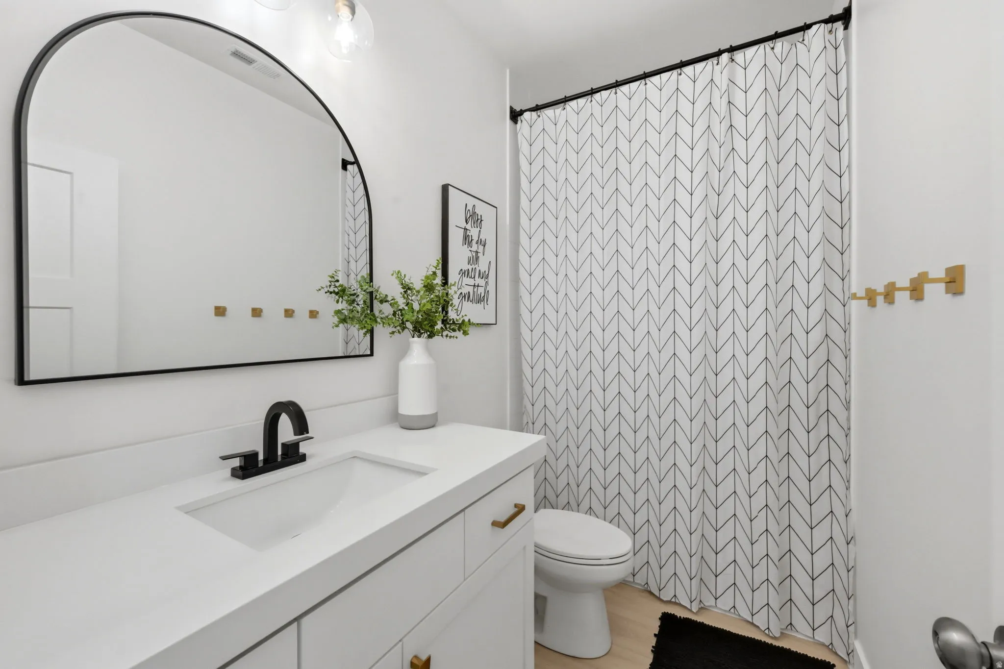 Bathroom featuring a white vanity with integrated sink, black faucet, and brass-tone hardware