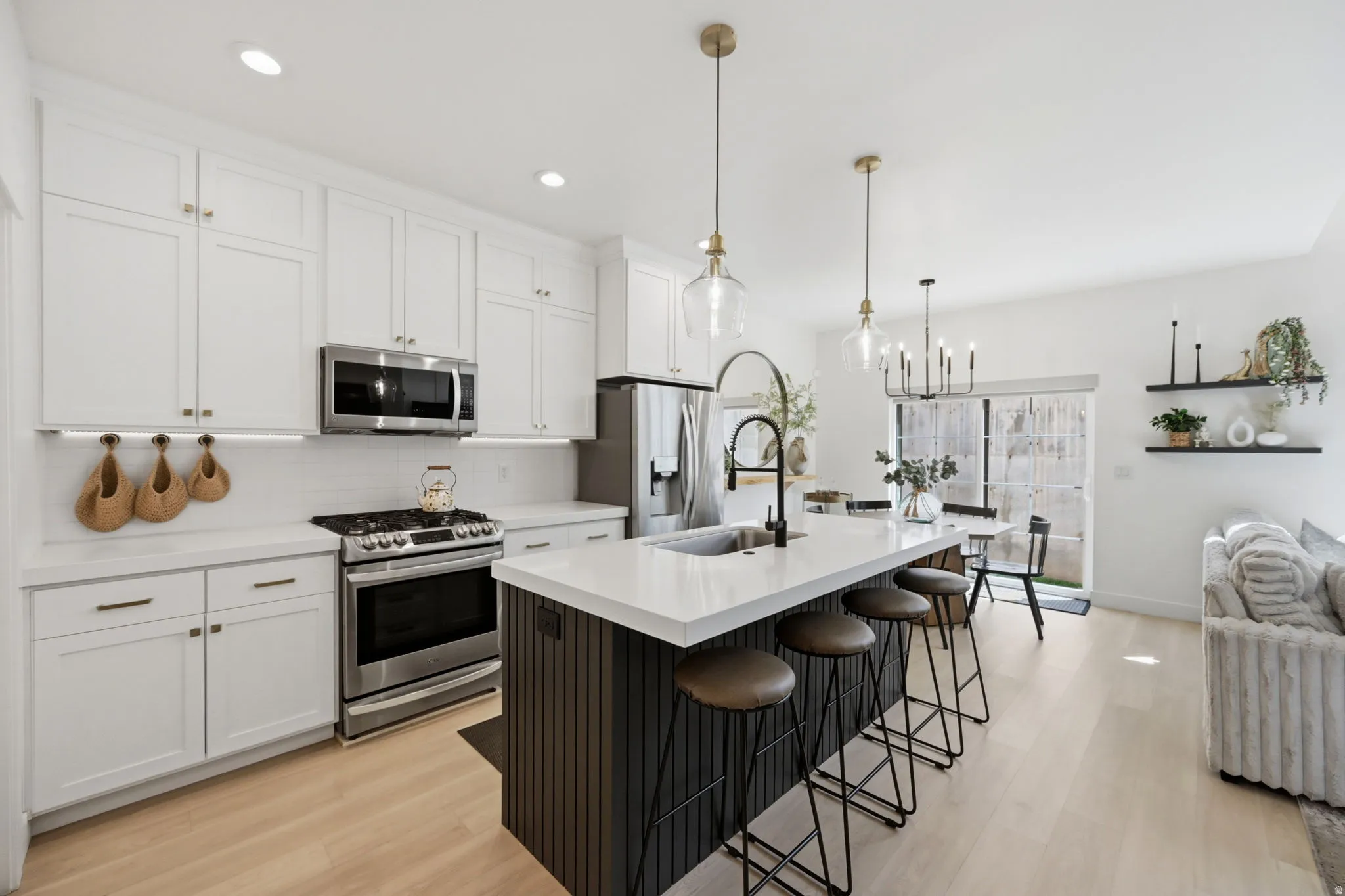 Contemporary kitchen featuring white shaker cabinetry, stainless steel appliances, and a central island with a white quartz countertop