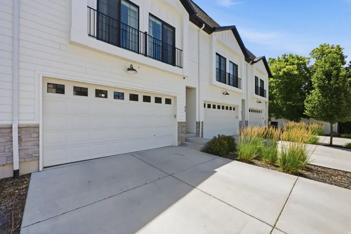 Modern townhome exterior featuring white siding, black-framed windows, and stone accents