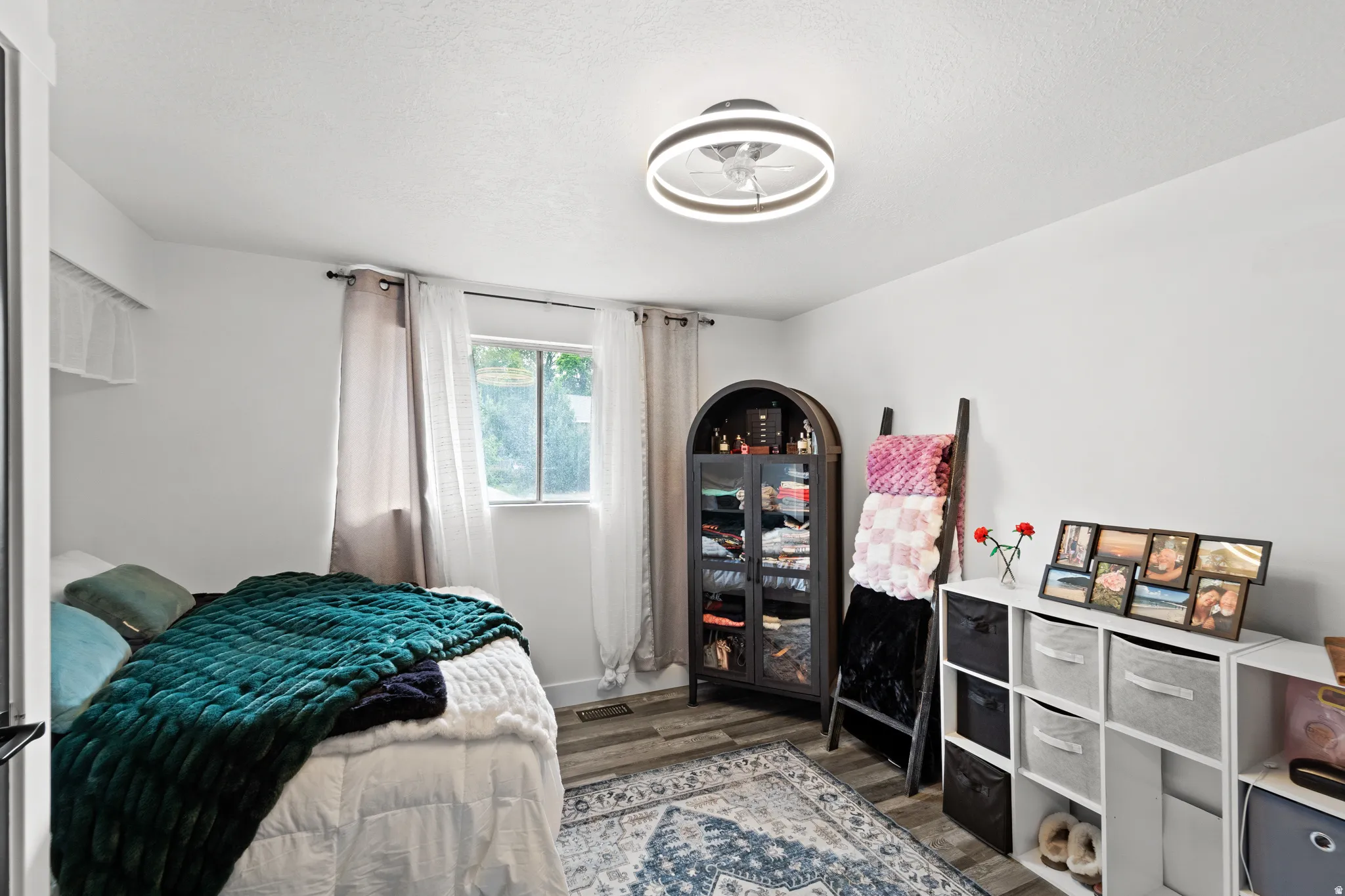Bedroom featuring wood-finish flooring, a contemporary ceiling light fixture, and a window with natural light