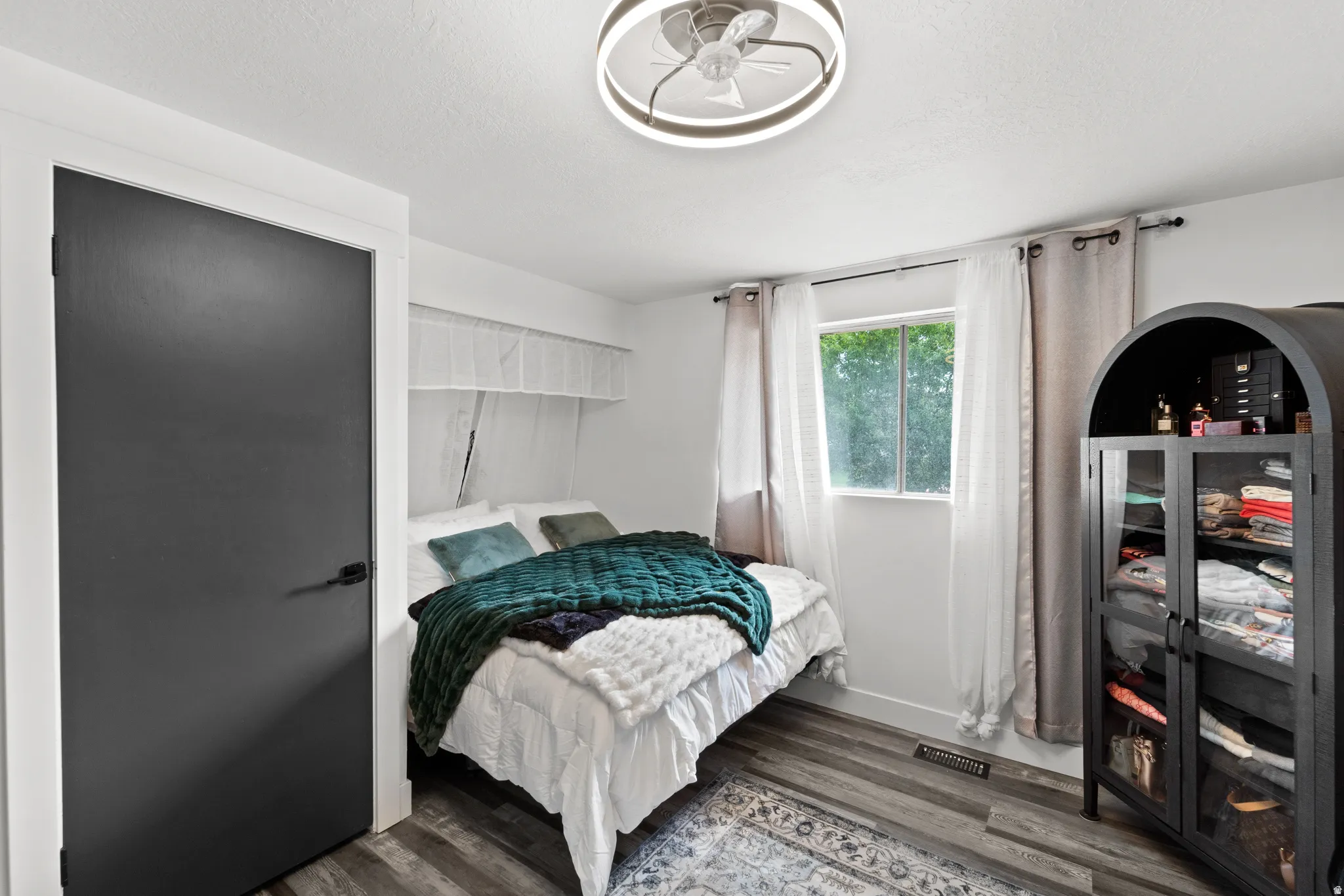Room featuring modern wood-finish flooring, a contemporary ceiling fan with integrated lighting, a dark interior door with dark hardware, and a window providing natural illumination