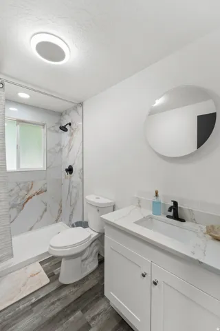 Bathroom featuring a white vanity with an integrated sink, black faucet, and a round frameless mirror