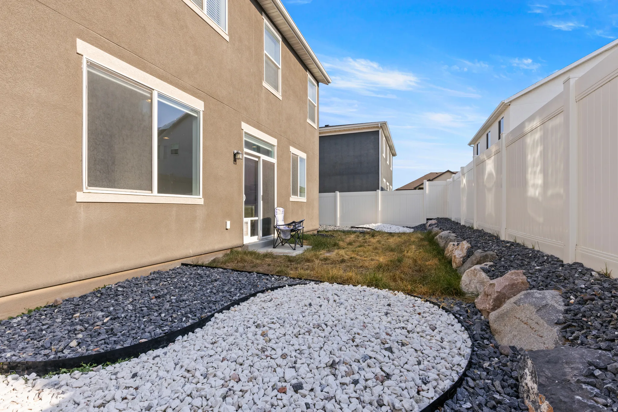 Backyard featuring a privacy fence, landscaping with decorative rocks, and a sliding glass patio door