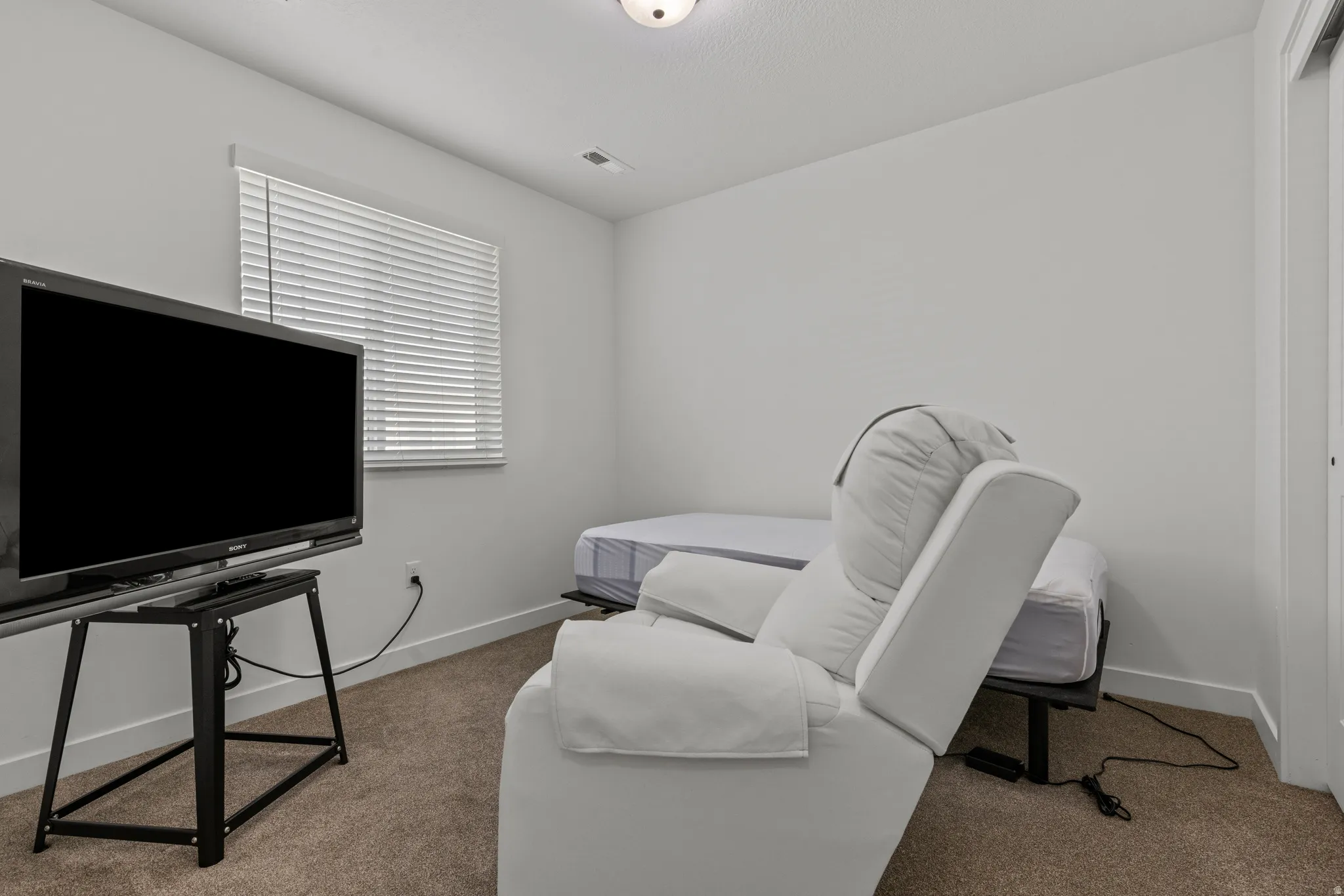 Carpeted room with a single window featuring horizontal blinds