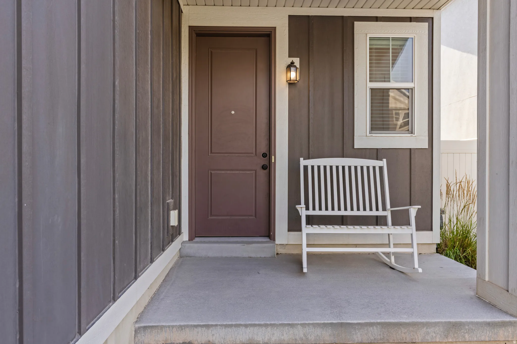 Front entry featuring a brown paneled door, exterior wall lantern, and board-and-batten siding