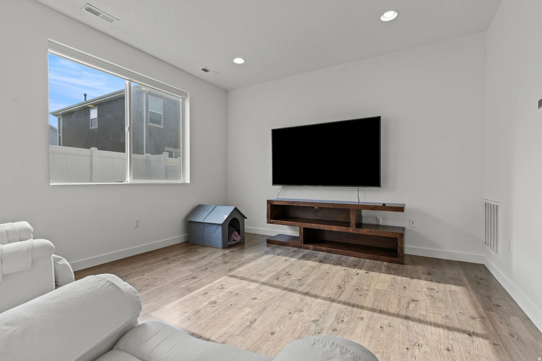 Living area with wood-finish flooring, recessed lighting, and a large window