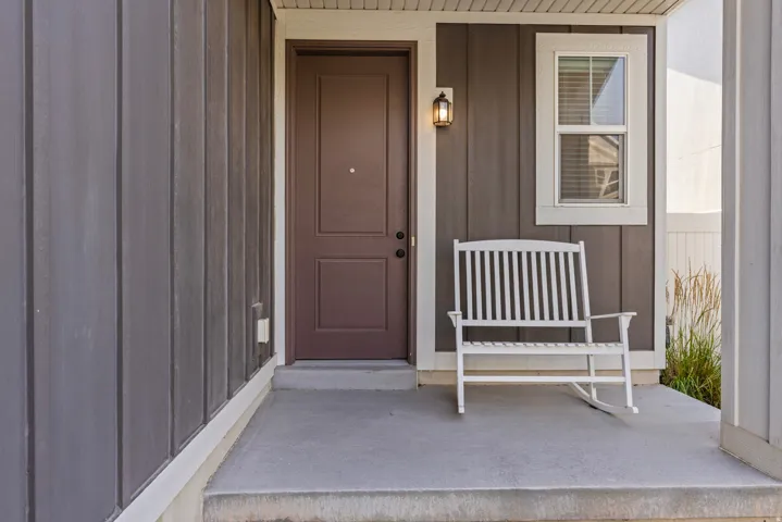 Front entry featuring a brown paneled door, exterior wall lantern, and board-and-batten siding