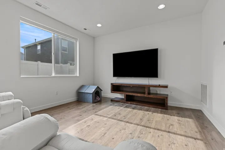 Living area with wood-finish flooring, recessed lighting, and a large window