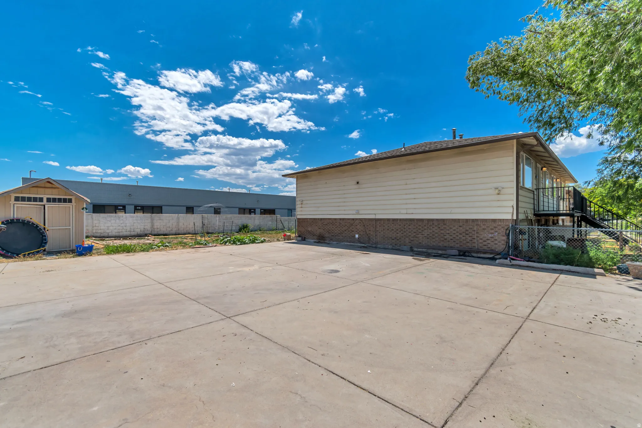 Expansive concrete patio area with a detached storage shed