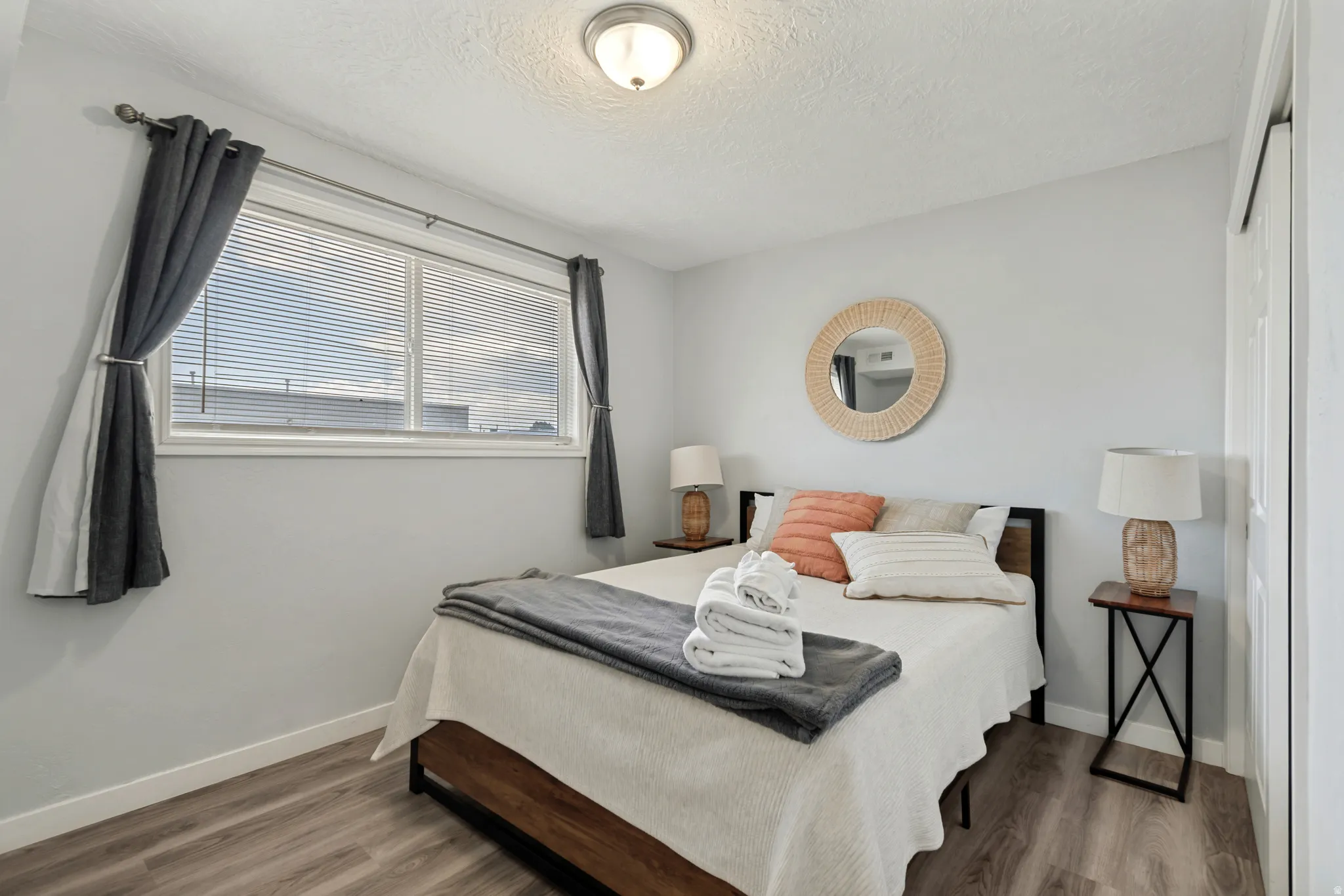 Interior room featuring a large window with blinds, wood-finish flooring, light gray walls, a flush-mount ceiling light, and a white sliding door